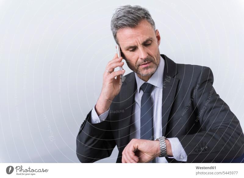 Geschäftsmann telefoniert und überprüft die Uhrzeit Kompetenz kompetent Brustbild Oberkörper telefonieren anrufen Anruf telephonieren Businessmann