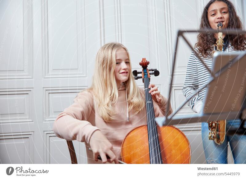 Zwei Mädchen spielen zusammen Cello und Saxophon weiblich Musik Kind Kinder Kids Mensch Menschen Leute People Personen Musiknoten Noten Notenblatt Notenblaetter