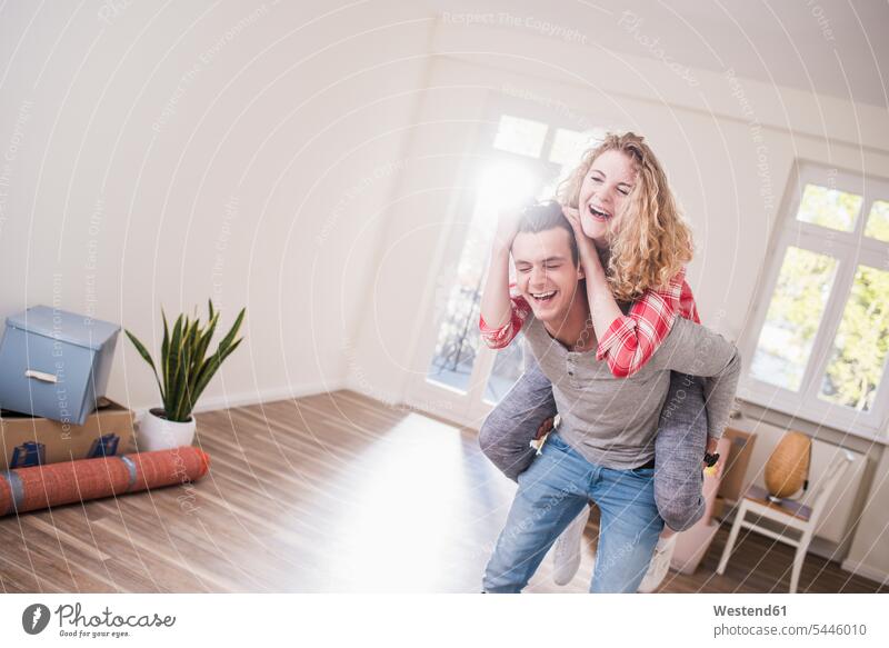 Verspieltes junges Paar in neuem Zuhause lachen Spaß Spass Späße spassig Spässe spaßig Wohnung wohnen Wohnungen Pärchen Paare Partnerschaft positiv Emotion