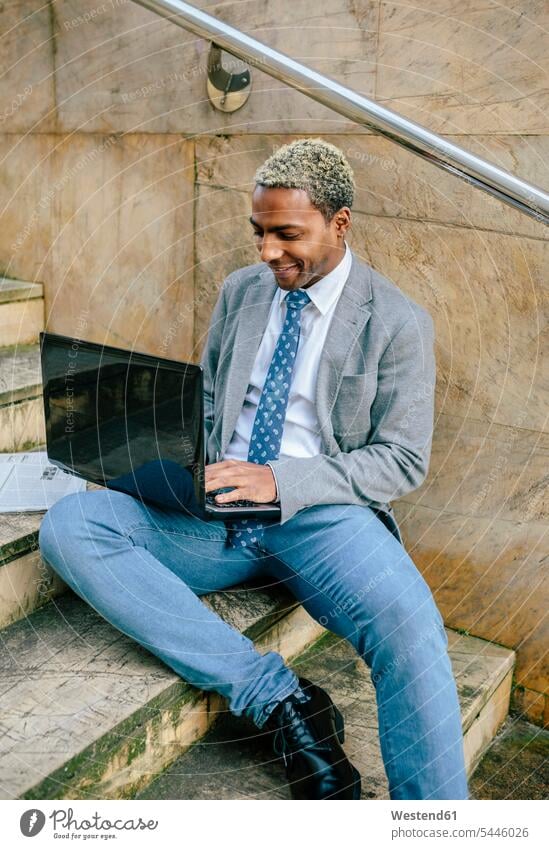 geschäftsmann, der auf einer Treppe sitzt und einen Laptop benutzt blond blonde Haare blondes Haar sitzen sitzend Treppenaufgang arbeiten Arbeit Notebook
