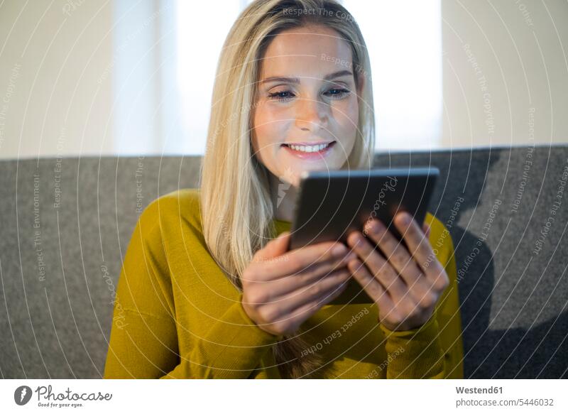 Porträt einer lächelnden Frau, die mit einem Mini-Tablett auf der Couch sitzt weiblich Frauen Tablet Computer Tablet-PC Tablet PC iPad Tablet-Computer Portrait