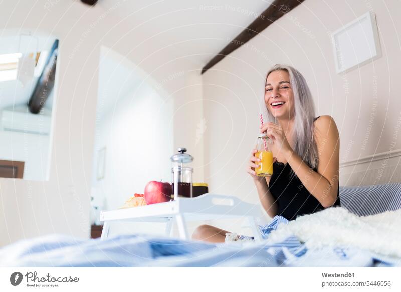 Glückliche junge Frau beim Frühstück im Bett Betten weiblich Frauen glücklich glücklich sein glücklichsein frühstücken Erwachsener erwachsen Mensch Menschen