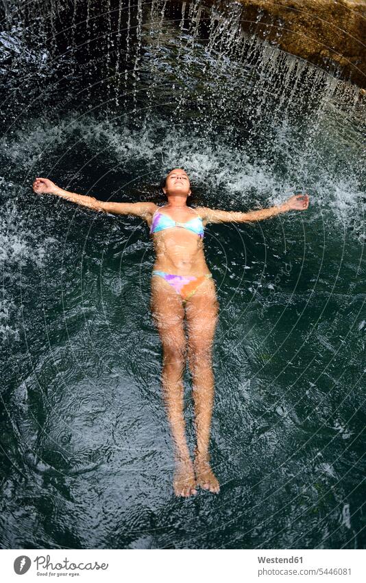 Junge Frau schwimmt im Wasser im Pool mit Wasserfall weiblich Frauen Erwachsener erwachsen Mensch Menschen Leute People Personen Urlaub Ferien Reise Travel