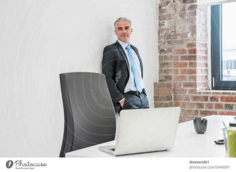 Ein reifer Geschäftsmann steht im Amt und sieht zuversichtlich aus Europäer Kaukasier Europäisch kaukasisch Internet Laptop Notebook Laptops Notebooks