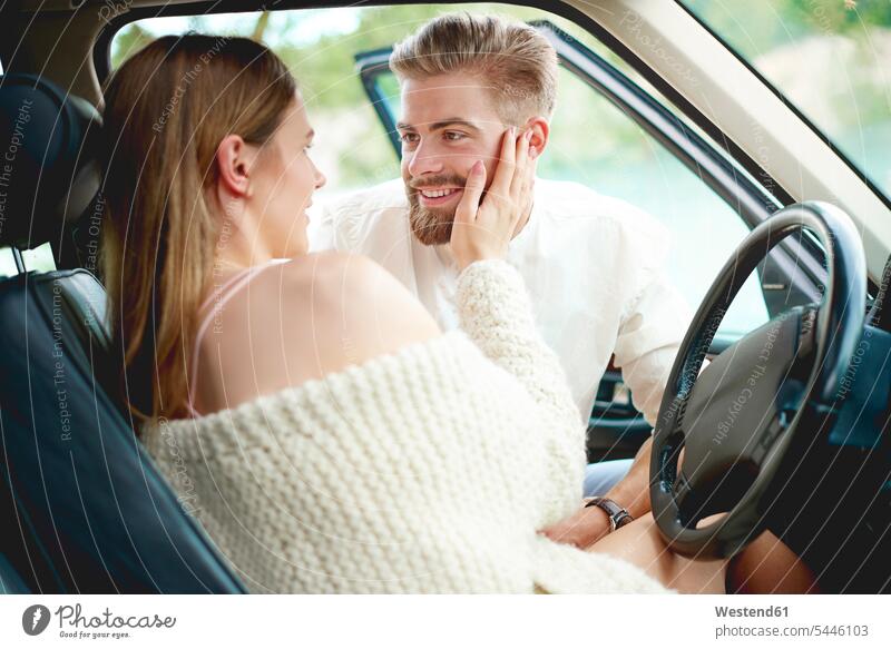Zärtliches junges Paar im Auto glücklich Glück glücklich sein glücklichsein Wagen PKWs Automobil Autos Liebe lieben Pärchen Paare Partnerschaft lächeln ansehen