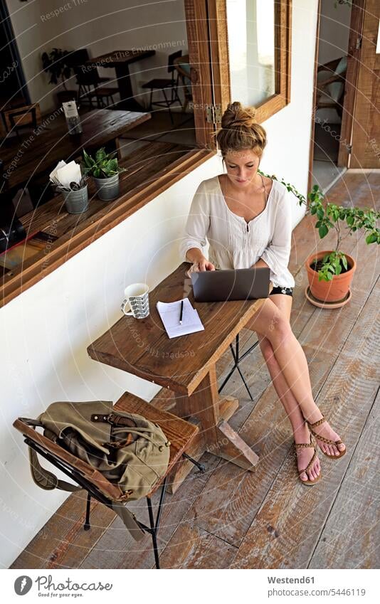 Junge Frau sitzt mit Laptop auf der Veranda eines Cafés Notebook Laptops Notebooks weiblich Frauen Computer Rechner Erwachsener erwachsen Mensch Menschen Leute