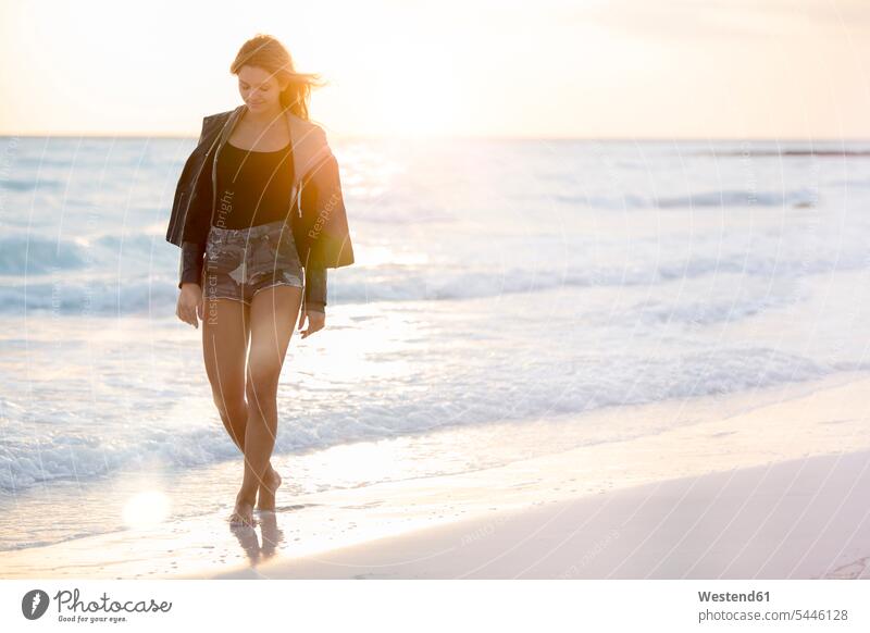 Junge Frau genießt den Strand bei Sonnenuntergang Auszeit Alles hinter sich lassen abschalten entspannen Beach Straende Strände Beaches Urlaub Ferien Meer Meere