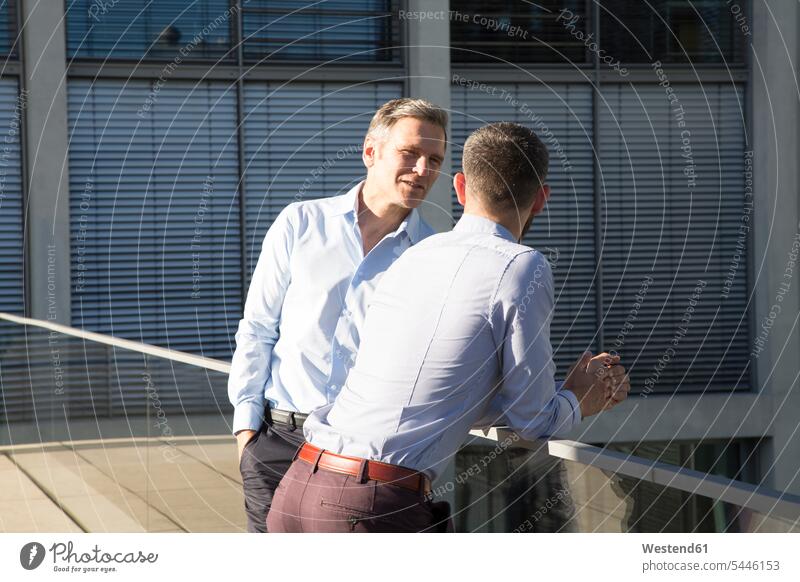 Zwei Geschäftsleute unterhalten sich auf einer Brücke sprechen reden Kollegen Arbeitskollegen Geschäftsmann Businessmann Businessmänner Geschäftsmänner