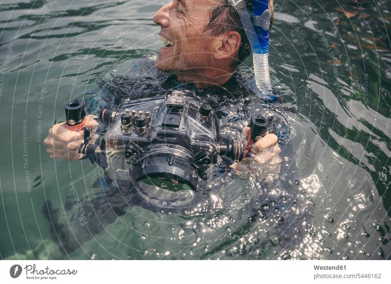 Glücklicher Mann mit Unterwasser-DSLR-Kamerakoffer in einem See Fotoapparat Fotokamera Männer männlich tauchen Taucher lachen Kameras Erwachsener erwachsen