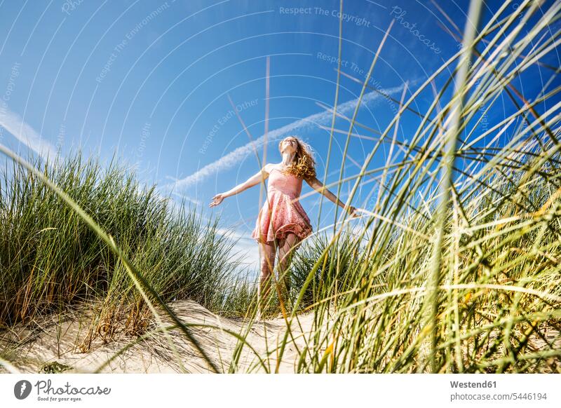 Niederlande, Zandvoort, glückliche Frau, die mit ausgestreckten Armen in den Dünen steht weiblich Frauen Sanddüne Sanddünen stehen stehend Strand Beach Straende