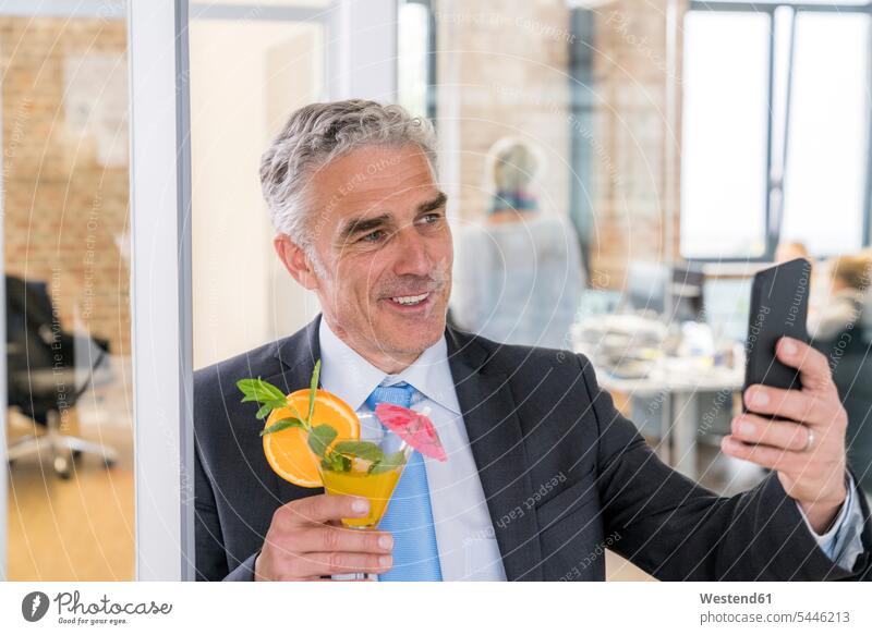 Reifer Geschäftsmann, der einen Cocktail trinkt und ein Selfie macht Cocktails Longdrink Longdrinks trinken telefonieren anrufen Anruf telephonieren feiern