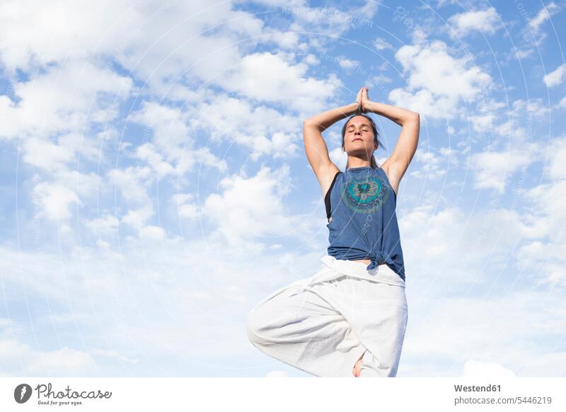 Frau macht eine Yoga-Übung unter einem wolkenverhangenen Himmel Uebung Übungen Uebungen weiblich Frauen Erwachsener erwachsen Mensch Menschen Leute People