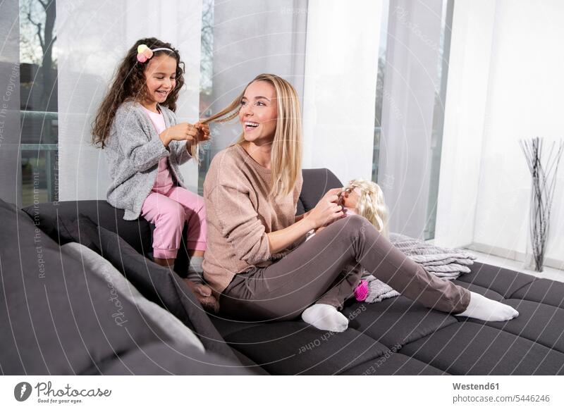 Kleines Mädchen flechtet das Haar seiner Mutter auf der Couch Mami Mutti Mütter Mama weiblich Sofa Couches Liege Sofas flechten Eltern Familie Familien Mensch
