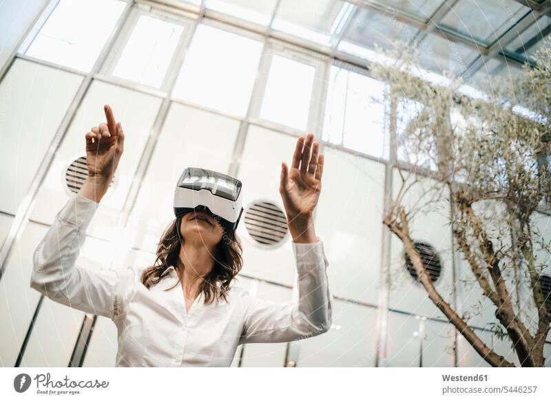 Geschäftsfrau mit VR-Brille im Büro Office Büros tasten stehen stehend steht Virtual Reality Brille Virtual-Reality-Brille Virtual Reality-Brille VR Brille