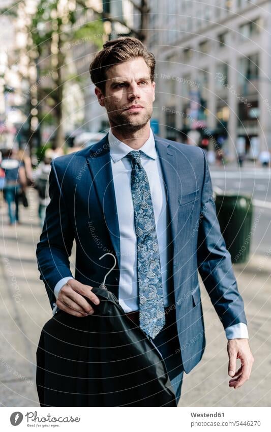 Gutaussehender Geschäftsmann geht in Manhattan spazieren, trägt Jacke auf einem Kleiderbügel Jacken Pendler gehen gehend Businessmann Businessmänner