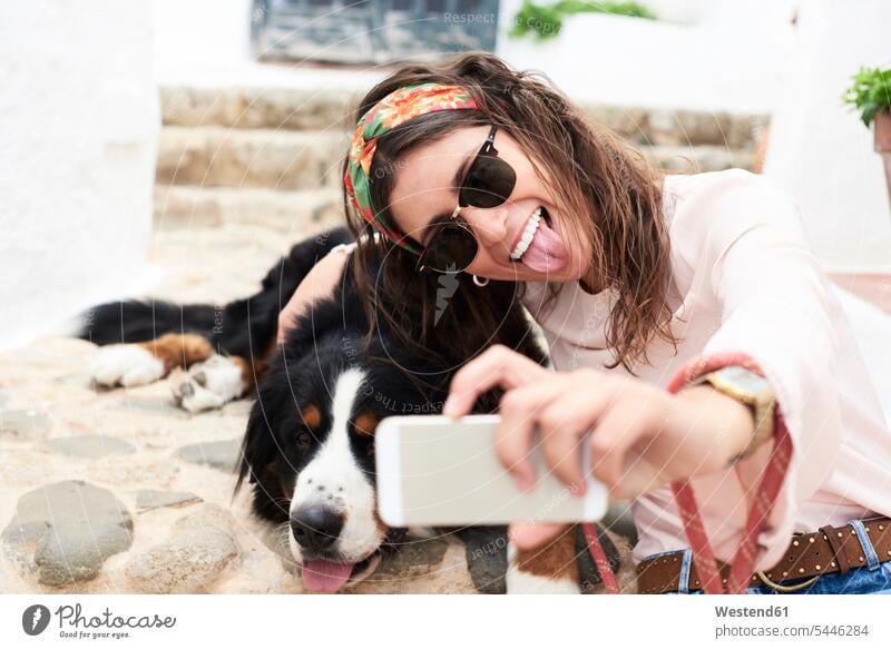 Brünettes Mädchen macht Selfie, müder Berner Sennenhund liegt auf dem Boden Hund Hunde Frau weiblich Frauen Freizeit Muße Smartphone iPhone Smartphones