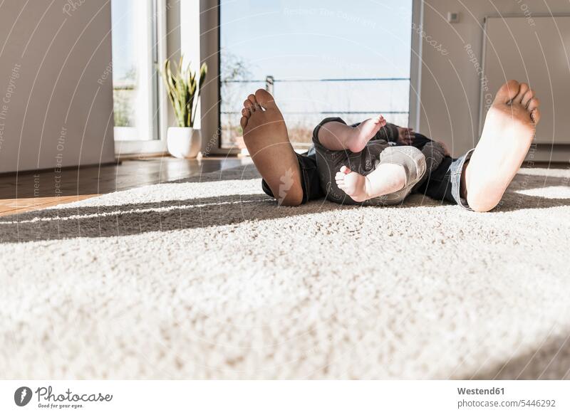 Vater und kleiner Sohn schlafen auf Teppich, Blick auf nackte Füße Zuhause zu Hause daheim Papas Väter Vati Vatis Papis ausruhen Rast Erholung erholen schlafend