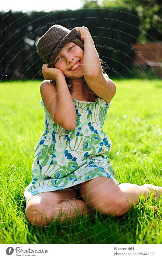 Fröhliches verspieltes Mädchen mit Hut im Garten sitzend Hüte lächeln sitzt Gärten Gaerten Spaß Spass Späße spassig Spässe spaßig weiblich Kind Kinder Kids