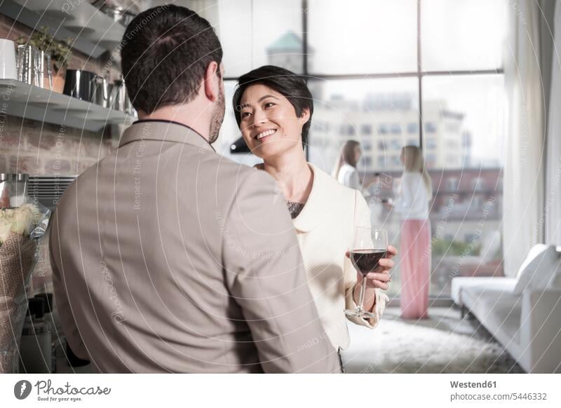 Mann und Frau mit Rotweinglas beim geselligen Beisammensein in einer Stadtwohnung feiern unterhalten Zuhause zu Hause daheim lächeln Freunde Freundschaft