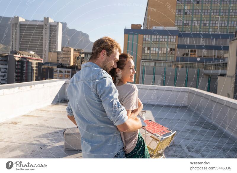 Junges Paar feiert auf einer Dachterrasse und umarmt sich bei Sonnenuntergang gemischtrassige Person Freizeit Muße Sommer Sommerzeit sommerlich feiern Nähe nah