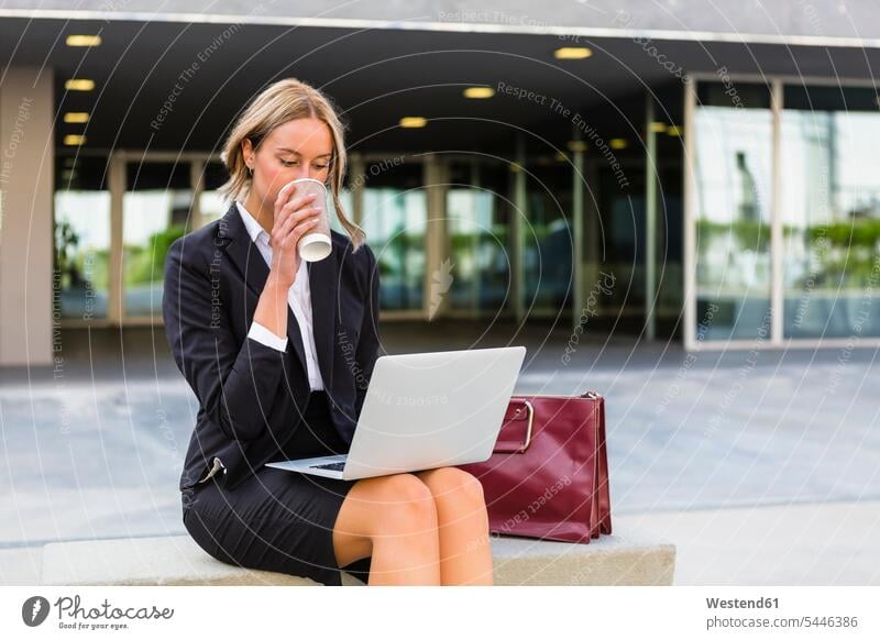 Geschäftsfrau mit modischer Ledertasche und Kaffee zum Mitnehmen auf der Bank sitzend und auf den Laptop schauend Geschäftsfrauen Businesswomen Businessfrauen