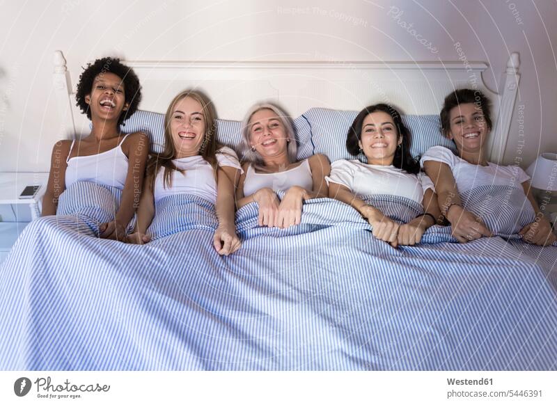 Porträt von glücklichen Freundinnen, die nebeneinander im Bett liegen Portrait Porträts Portraits lachen liegend liegt Frau weiblich Frauen Betten positiv