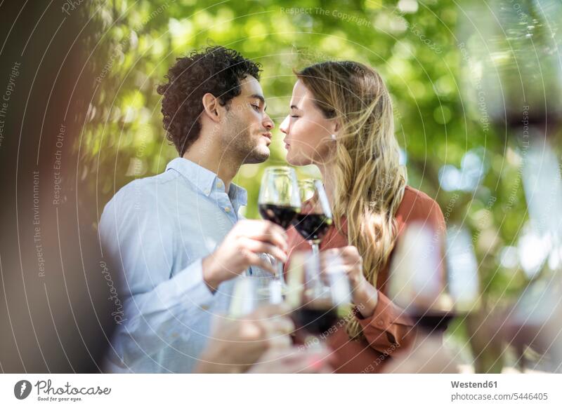 Pärchen küsst sich beim Mittagessen im Garten mit Rotwein Rotweine Wein Weine feiern küssen Küsse Kuss Paar Paare Partnerschaft Alkohol Alkoholische Getraenke