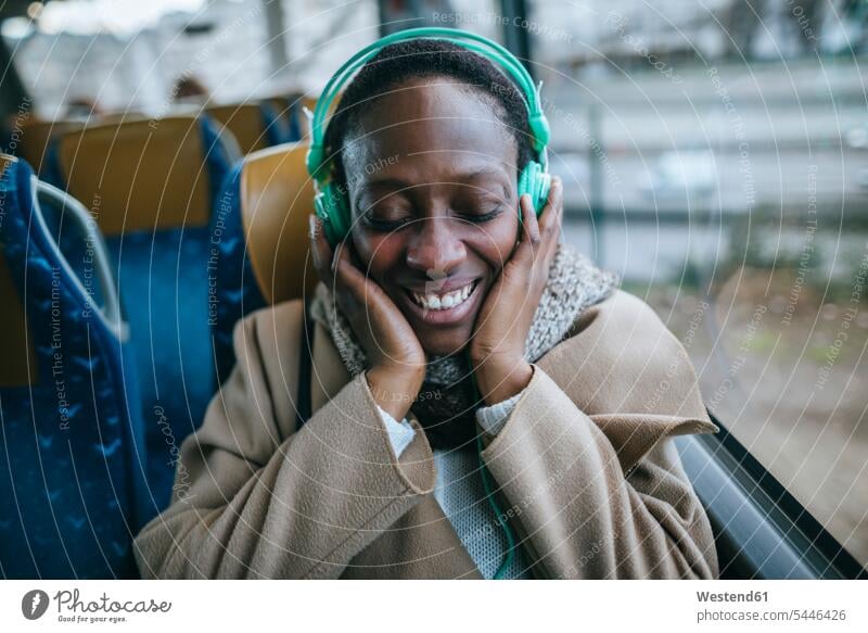 Glückliche junge Frau hört Musik in einem Bus weiblich Frauen Kopfhörer Kopfhoerer Portrait Porträts Portraits Erwachsener erwachsen Mensch Menschen Leute