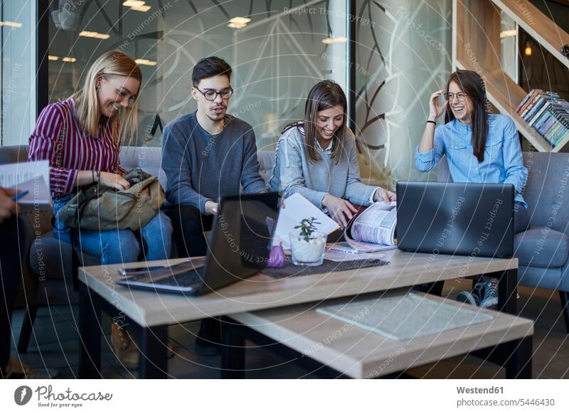 Gruppe von Freunden sitzt mit Laptop und Dokumenten in einem Café zusammen Unterlagen Gemeinsam Zusammen Miteinander Notebook Laptops Notebooks Cafe Kaffeehaus