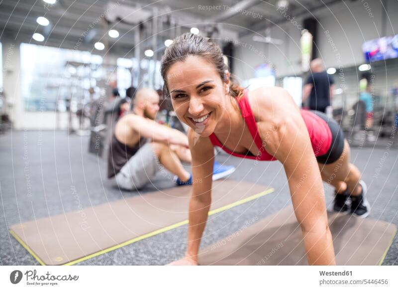 Porträt einer lächelnden jungen Frau, die im Fitnessstudio trainiert Liegestützen Push-Up Pushups Push-Ups Fitnessclubs Fitnessstudios Turnhalle trainieren