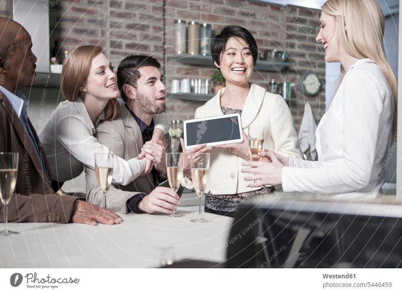 Glückliche Frau zeigt Freunden mit Champagnergläsern zu Hause Tablette Tablet Computer Tablet-PC Tablet PC iPad Tablet-Computer Zuhause daheim feiern Sekt