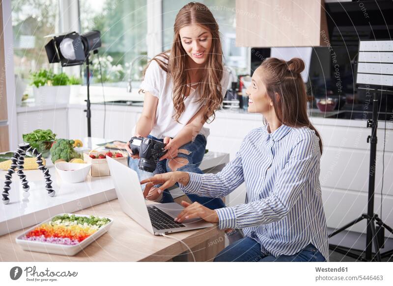 Zwei Food-Blogger mit Laptop und Kamera in der Küche Fotokamera Kameras Rechner Laptops Notebook Notebooks Leute Menschen People Person Personen erwachsen