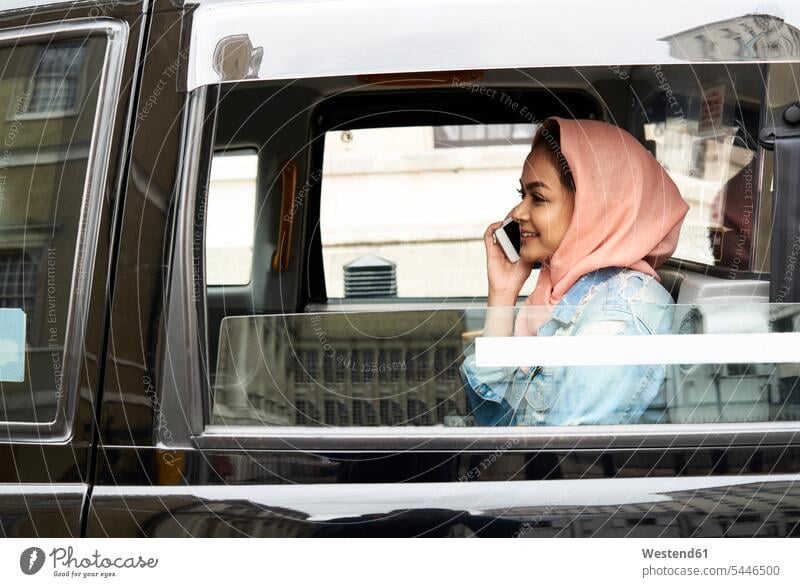 Großbritannien, England, London, junge Frau mit Hijab am Telefon im Taxi Handy Mobiltelefon Handies Handys Mobiltelefone telefonieren anrufen Anruf