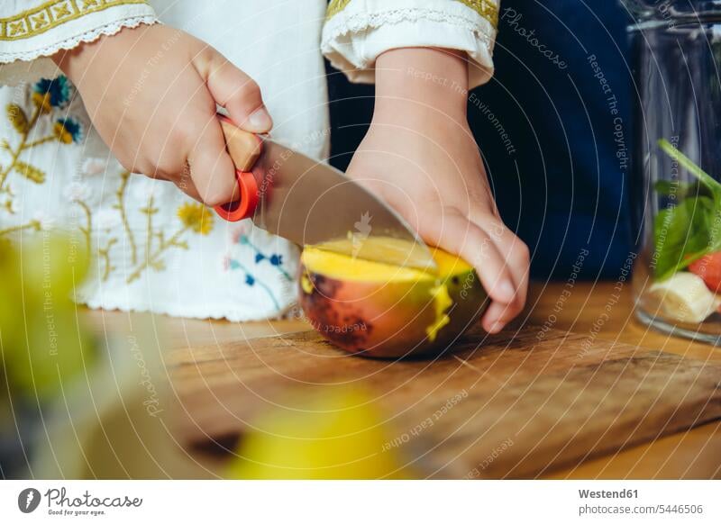 Mädchen schneidet eine Mango mit einem Kindermesser Mangos Küche weiblich schneiden Obst Früchte Essen Food Food and Drink Lebensmittel Essen und Trinken