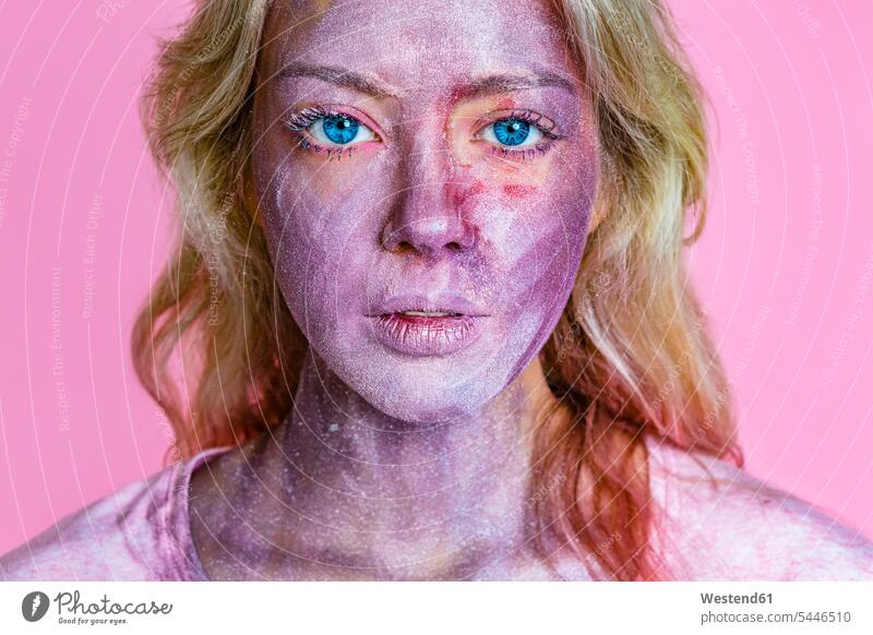 Porträt einer jungen Frau mit metallischem Schimmer im Gesicht vor rosa Hintergrund Pigment Farbpigmente Pigmente weiblich Frauen Glimmer schhimmern Erwachsener