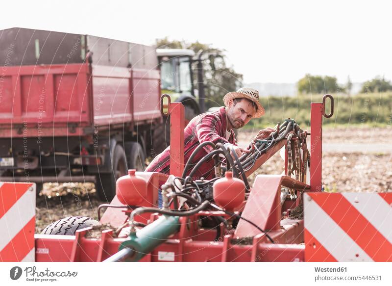 Landwirt auf dem Feld untersucht landwirtschaftliche Maschine Mann Männer männlich Felder Landmaschine Landmaschinen landwirtschaftliche Maschinen Bauer