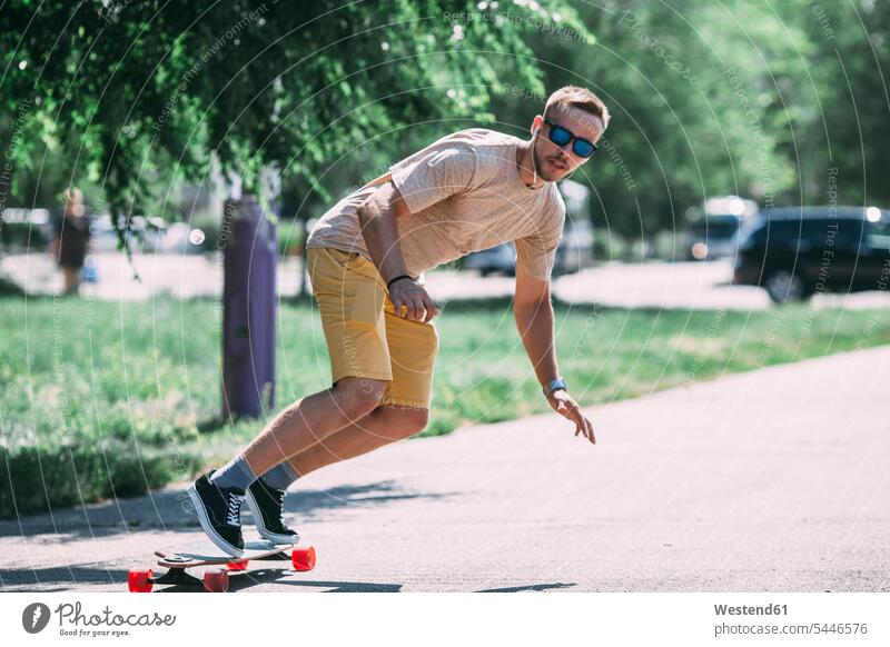 Junger Mann fährt Skateboard auf der Straße fahren Skateboarder Skateboardfahrer Skateboarders Skater Rollbretter Skateboards Männer männlich Mensch Menschen