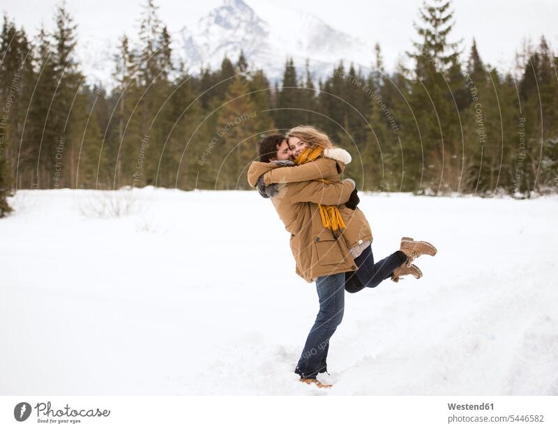 Glückliches junges Paar in schneebedeckter Winterlandschaft Pärchen Paare Partnerschaft Mensch Menschen Leute People Personen lachen Winterlandschaften Schnee