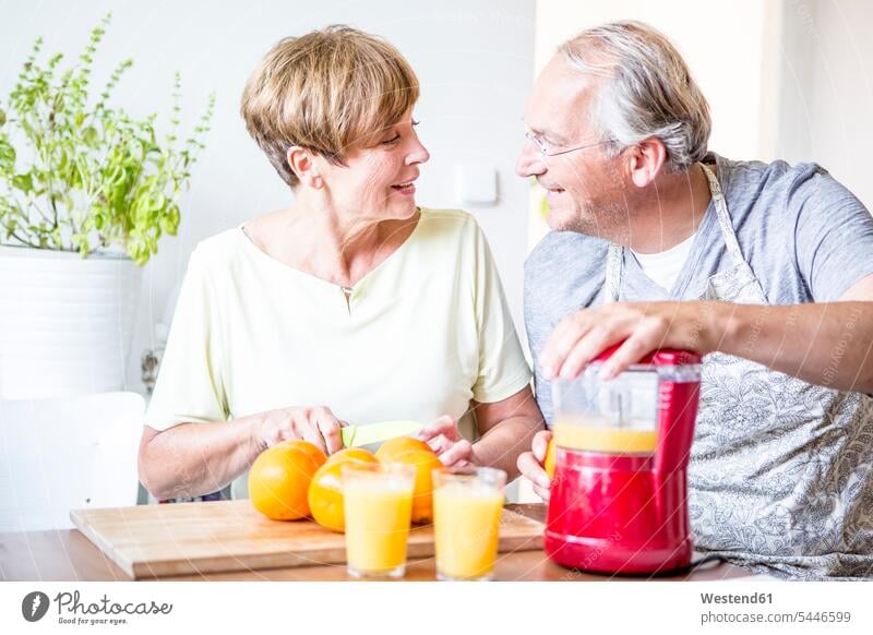 Älteres Ehepaar in der Küche bereitet frisch gepressten Orangensaft zu lächeln Apfelsinensaft O-Saft Paar Pärchen Paare Partnerschaft Fruchtsaft Fruchtsäfte