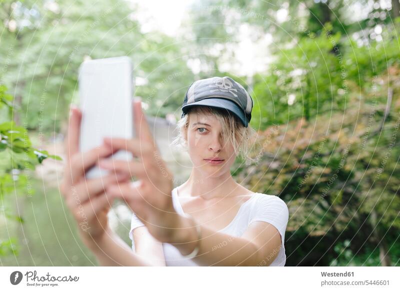 Junge Frau macht ein Selfie im Park Selfies Parkanlagen Parks weiblich Frauen Handy Mobiltelefon Handies Handys Mobiltelefone Erwachsener erwachsen Mensch