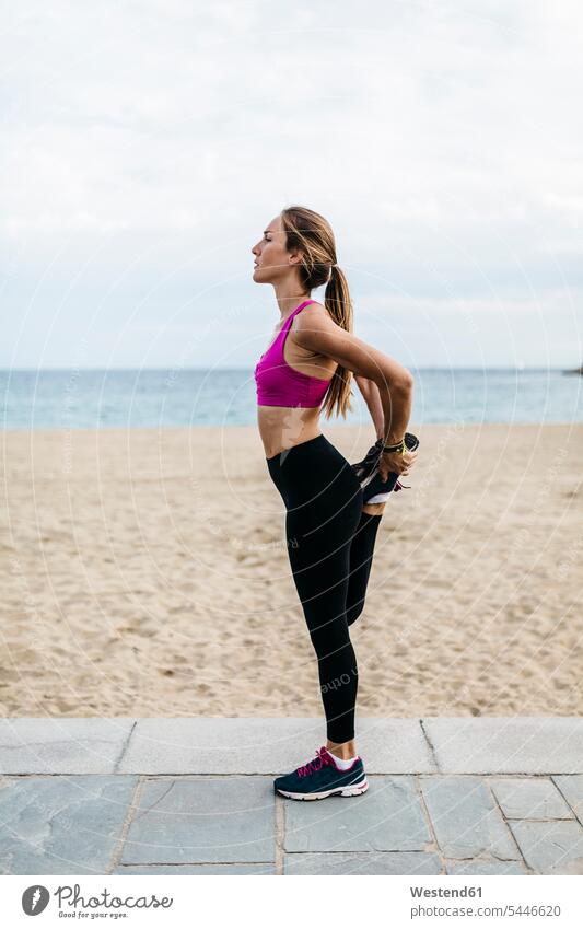 Junge Frau beim Stretching und Aufwärmen für das Training am Strand trainieren Beach Straende Strände Beaches weiblich Frauen dehnen strecken stehen stehend