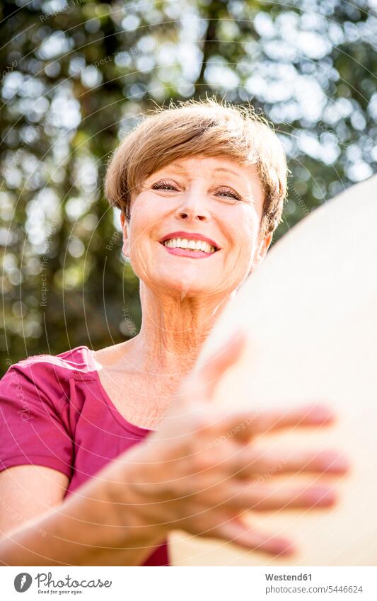 Porträt einer lächelnden älteren Frau, die einen Fitnessball im Freien hält Seniorin Seniorinnen alt Gymnastikball Sitzball weiblich Frauen trainieren Senioren