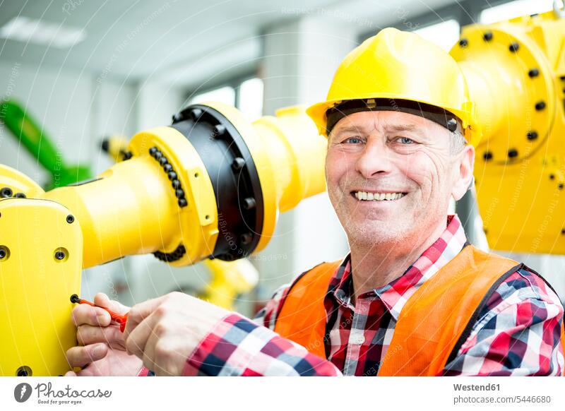 Porträt eines lächelnden Technikers, der an einem Industrieroboter arbeitet Fabrik Fabriken arbeiten Arbeit industriell Gewerbe Industrien Business