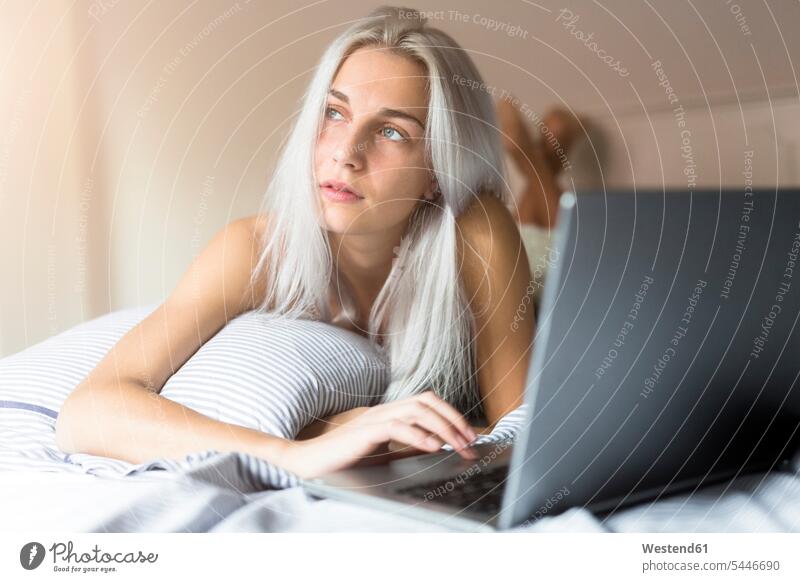Junge Frau liegt mit Laptop im Bett liegen liegend Notebook Laptops Notebooks weiblich Frauen Betten Computer Rechner Erwachsener erwachsen Mensch Menschen
