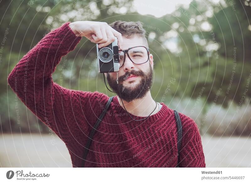 Porträt eines bärtigen Mannes mit Brille, der mit einer Oldtimer-Kamera fotografiert Portrait Porträts Portraits Männer männlich fotografieren Erwachsener