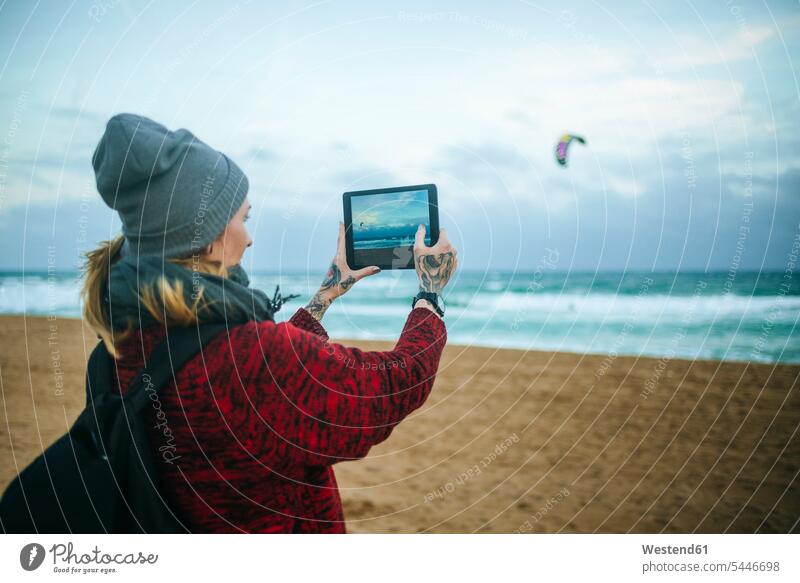 Junge Frau am Strand im Winter beim Fotografieren mit einer Tablette fotografieren Beach Straende Strände Beaches weiblich Frauen Tablet Computer Tablet-PC