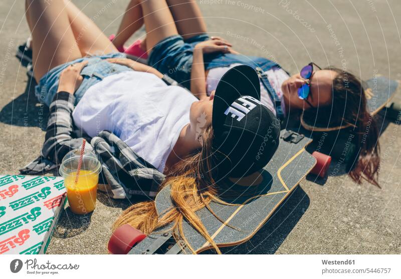 Zwei junge Frauen mit Longboards genießen den Sommer liegen liegend liegt Getränk zum mitnehmen Rückenlage auf dem Rücken auf dem Rücken liegen Sommerzeit