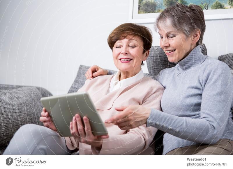 Zwei ältere Frauen sitzen auf einer Couch und schauen auf ein digitales Tablet Freundinnen Gemeinsam Zusammen Miteinander Tablet Computer Tablet-PC Tablet PC