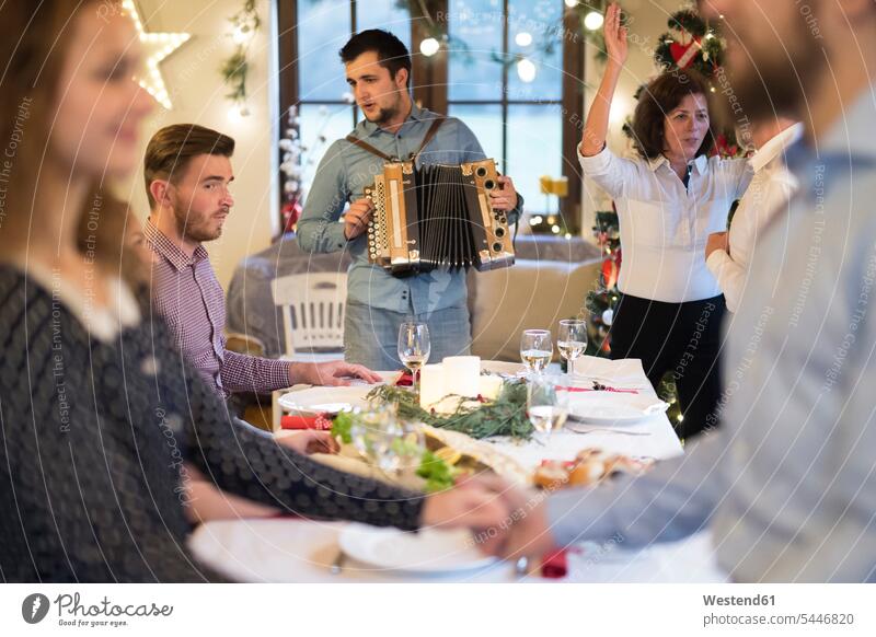 Junger Mann spielt zu Weihnachten Akkordeon für die Familie Akkordeons Schifferklaviere Christmas X-Mas X mas Familien feiern Tasteninstrument Tasteninstrumente