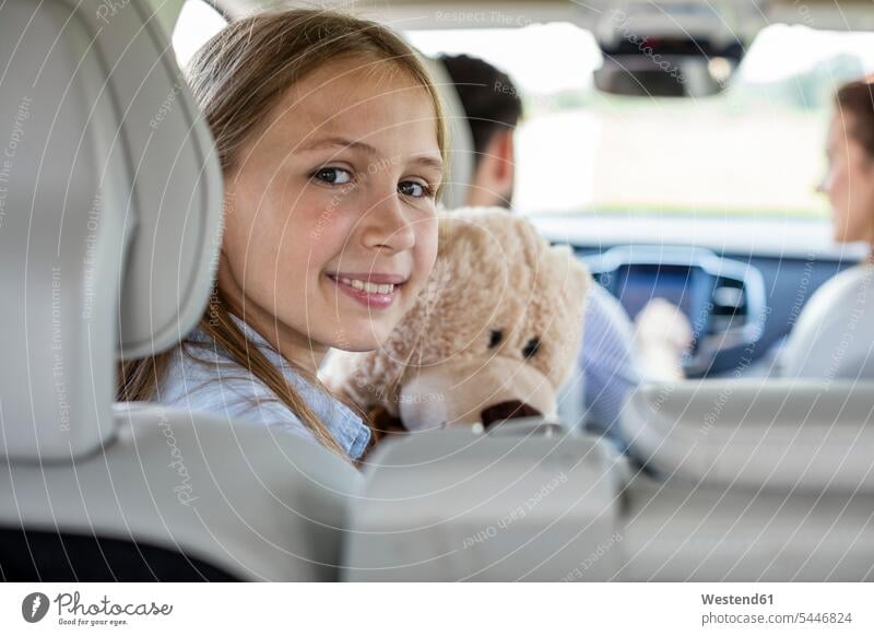 Glückliche Familie macht eine Autoreise, die Tochter schaut in die Kamera Vater Papas Väter Vati Vatis Papis fahren fahrend fahrender fahrendes Wagen PKWs